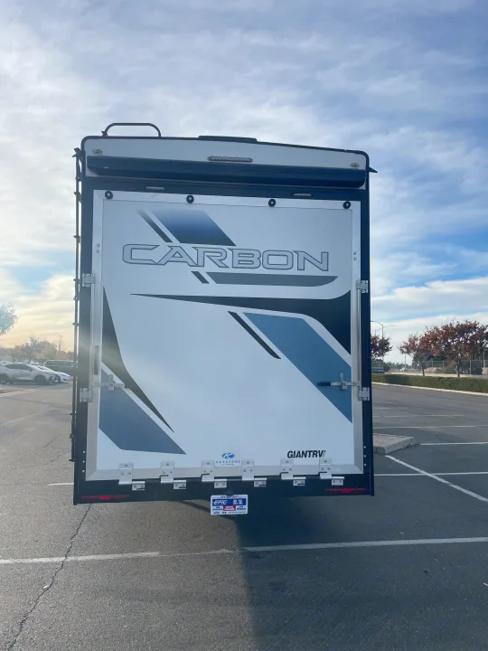 Back of a "Carbon" RV toy hauler trailer, featuring a rear ramp door. Ideal for your next rv rental adventure!. Keystone Carbon 2021