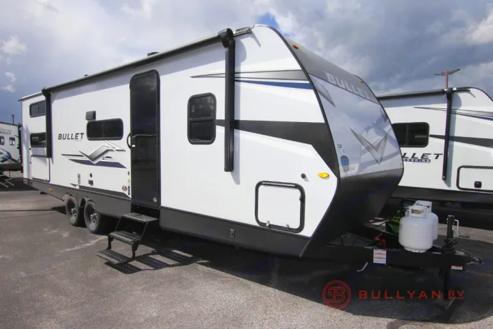 White Bullet travel trailer for RV rental, with black accents, awning, and propane tanks, ready for your trip.. Keystone Bullet 2024