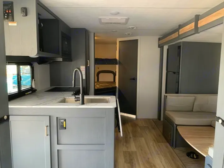 Spacious RV rental interior with kitchen, dinette, and bunk beds, ready for comfortable travel adventures.. Keystone Bullet 2024