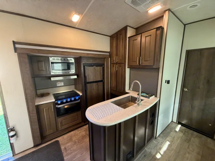 Spacious RV rental interior featuring a full kitchen with microwave, stove, fridge, sink, and ample storage for comfortable living.. Heartland Torque 2019
