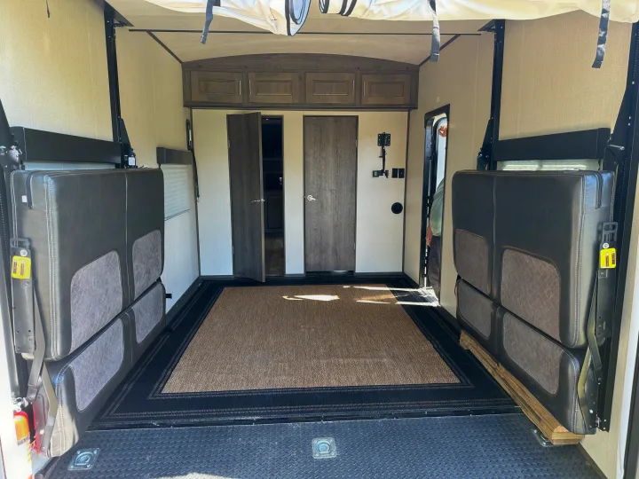 Interior of an RV rental toy hauler's garage, featuring fold-up sofas, rug, and rear loading access.. Heartland Torque 2019