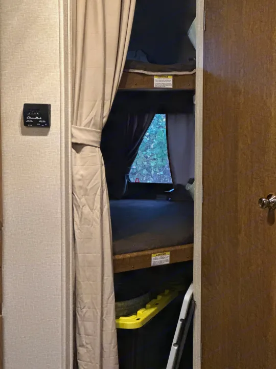 RV rental with bunk beds, privacy curtain, thermostat, and window view of trees. Perfect for a camper trip.. Crossroads RV Zinger 2016