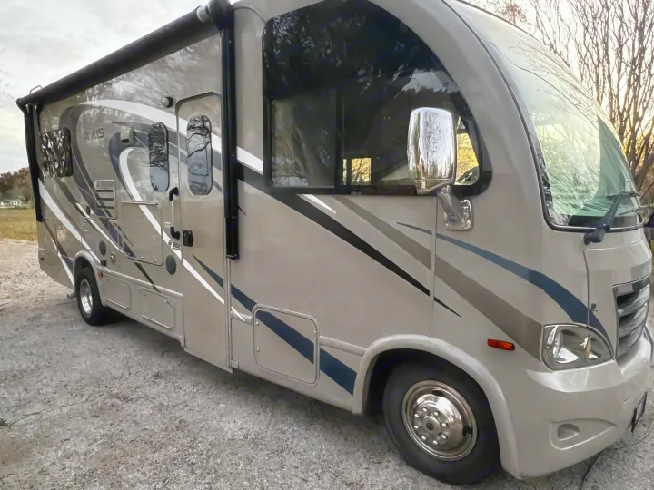 Modern Axis RV rental with light and dark stripes, parked on gravel. Perfect motorhome for your next travel adventure.. Thor Axis 2016