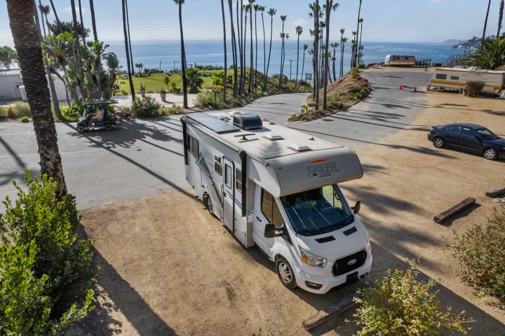 Explore coastal beauty! This Cross Trail RV rental awaits your adventure at a palm-lined oceanfront park.. COACHMEN Ford Transit 2022