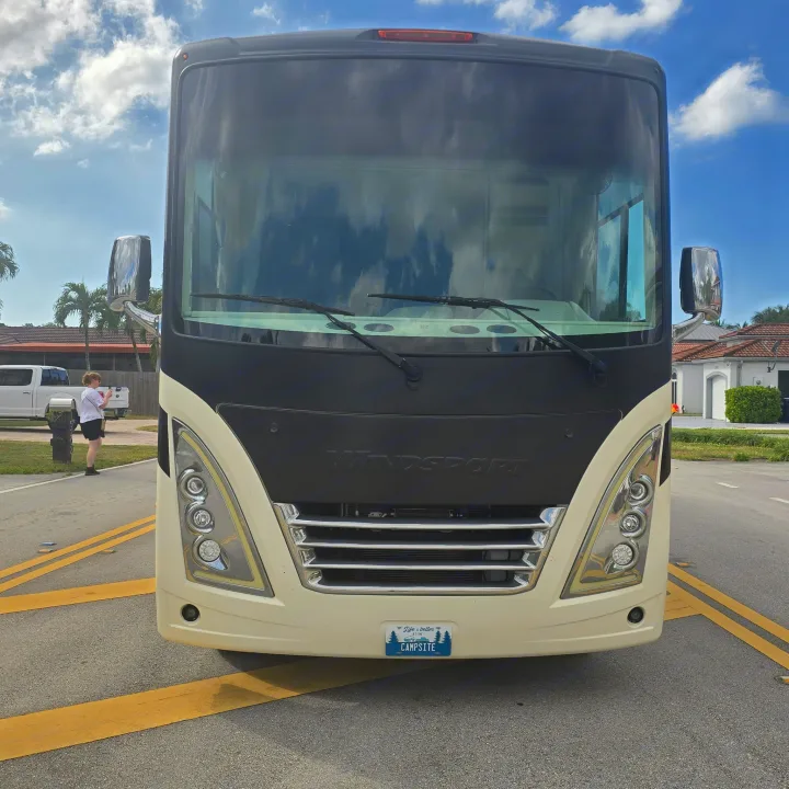 A large white and black Windsport RV, seen from the front, is parked on the road. Consider this RV rental for your next outdoor adventure!. Thor Windsport 2023