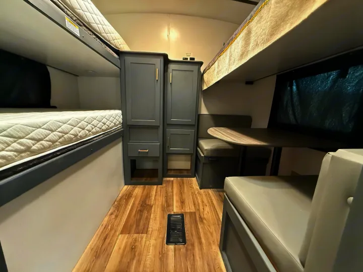 An RV rental interior showcasing comfortable bunk beds, a dining area with a table and bench seats, and built-in storage cabinets.. Keystone Bullet 2022
