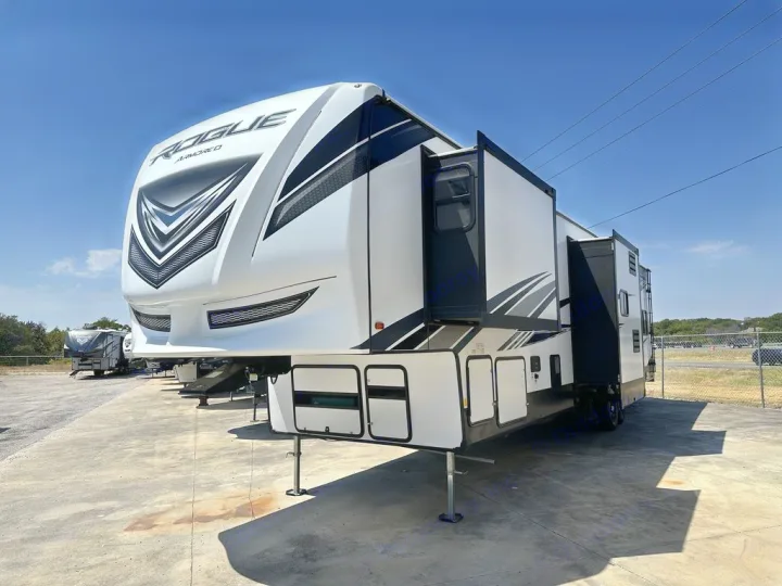 Modern white and black Rogue Armored fifth-wheel RV rental, parked with slide-outs extended, ready for adventure.. Forest River Vengeance Rogue Amored Toy Hauler 2021