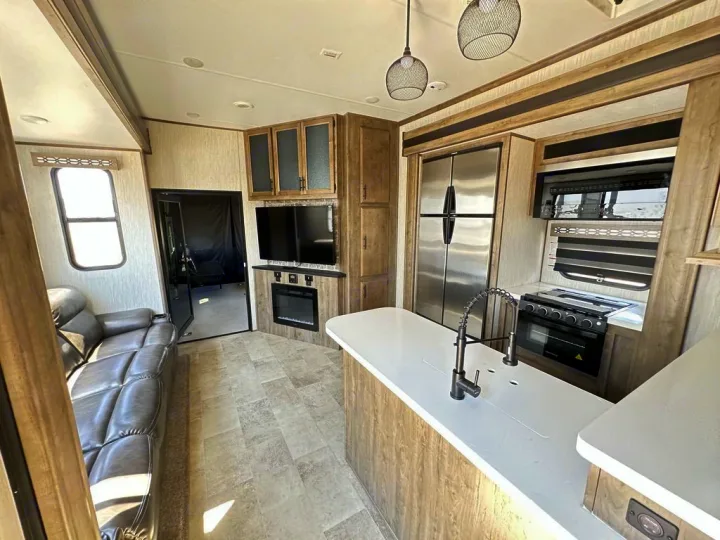 Spacious RV rental interior featuring a modern kitchen, comfortable living area with sofa, and fireplace.. Forest River Vengeance Rogue Amored Toy Hauler 2021