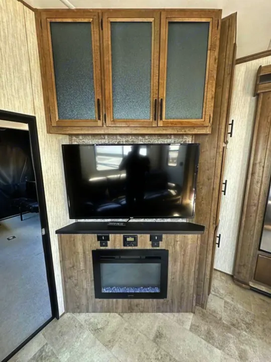 Explore this RV rental's modern interior with a built-in TV, electric fireplace, and overhead frosted cabinets.. Forest River Vengeance Rogue Amored Toy Hauler 2021