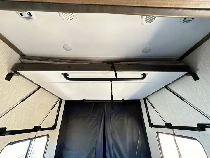 Compact RV rental interior featuring a clever fold-down bunk bed, optimizing space for sleeping or storage.. Forest River Vengeance Rogue Amored Toy Hauler 2021