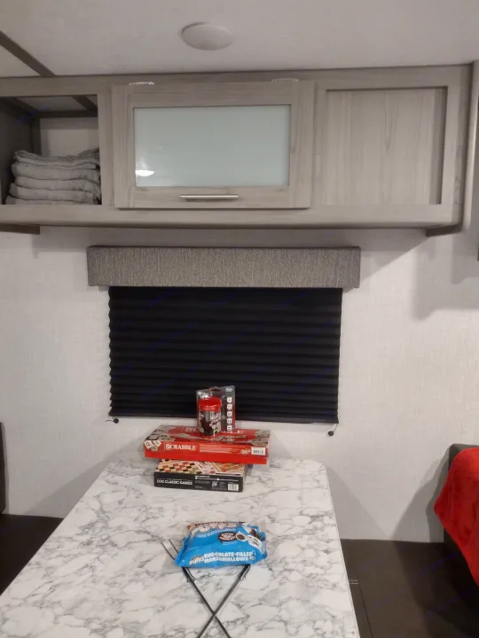 Inside an RV rental: stack of board games (Scrabble, 100 Classic Games), Yahtzee, marshmallows on a table for fun.. Coleman Lantern 2023