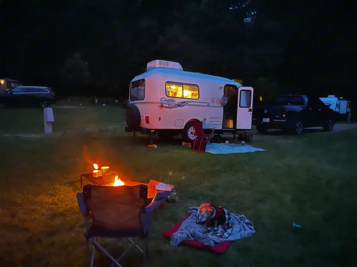 Night camping with an RV rental: a travel trailer, warm campfire, and a dog bundled on blankets. Perfect outdoor getaway.. Casita Casita Trailer 2009