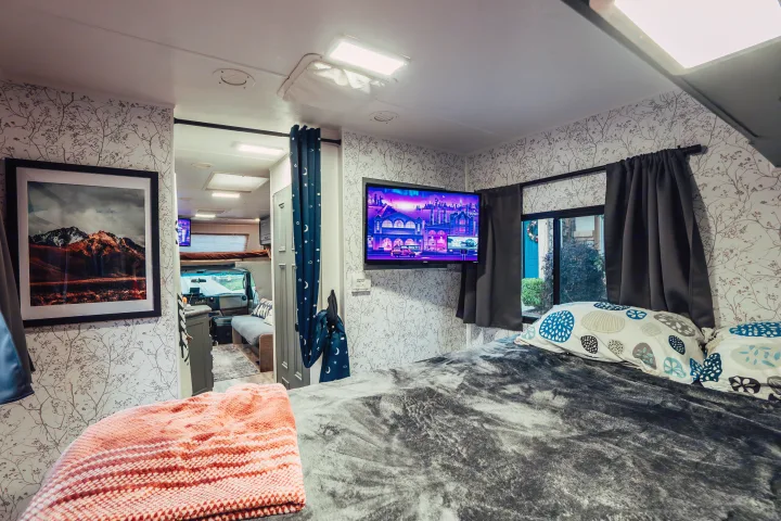 Cozy RV rental bedroom featuring a mounted TV, patterned walls, and a plush bed. A perfect mobile retreat.. Four Winds Four Winds Motorhome 2011