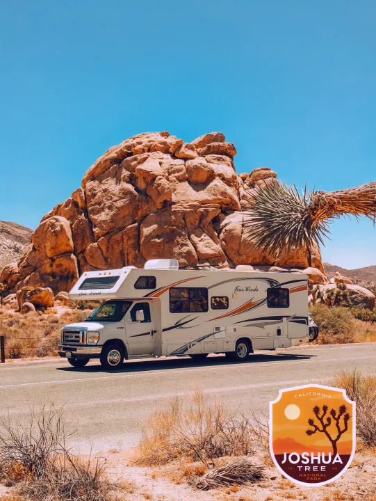 A Four Winds RV rental parked on a road in Joshua Tree National Park, with large rock formations and desert plants.. Four Winds Four Winds Motorhome 2011