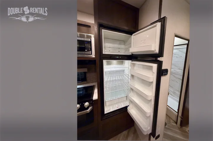 Double S RV rental kitchen: open fridge, microwave, and stovetop. A clean, equipped space for your next adventure!. KZ Sportster 2021