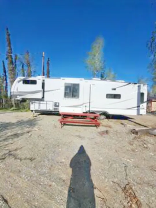 This spacious white travel trailer RV rental, featuring slide-outs and a red picnic table, is ready for outdoor escapes.. Alliance RV Paradigm 2024