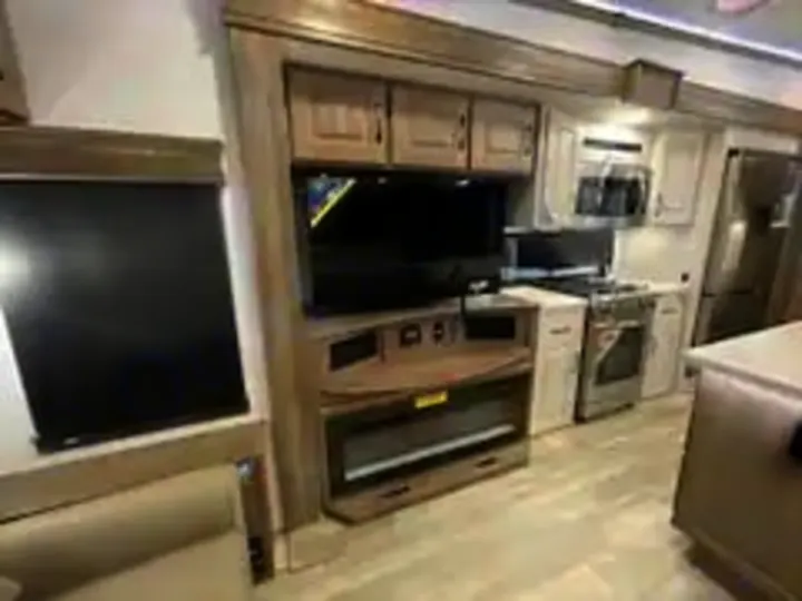 Experience comfortable RV rental travel! Modern RV interior shows living area with TV, fireplace, and well-equipped kitchen.. Alliance RV Paradigm 2024