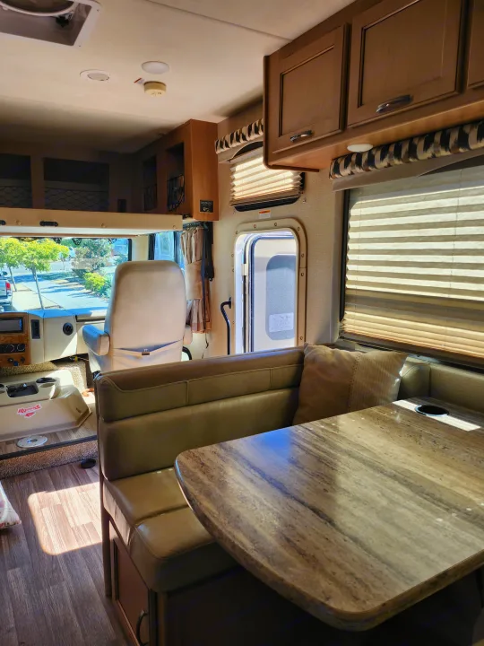 Spacious RV rental interior with a dinette, driver's area, and sunny windows. Perfect for adventures.. Thor A.C.E. 2018
