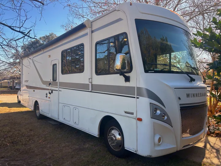 This white Winnebago motorhome with a grey stripe is an ideal rv rental, parked outdoors on a sunny day.. Winnebago Intent 2018