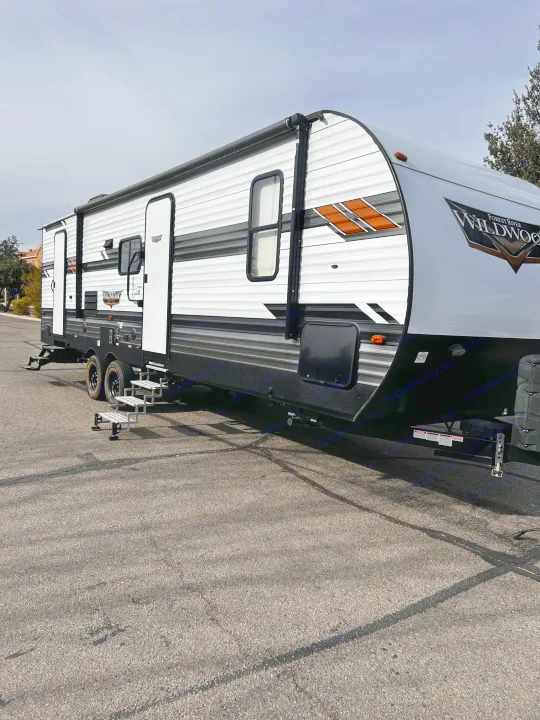 A pristine white and black Forest River Wildwood travel trailer, ideal for an RV rental adventure, parked on asphalt.. Forest River Wildwood 2022