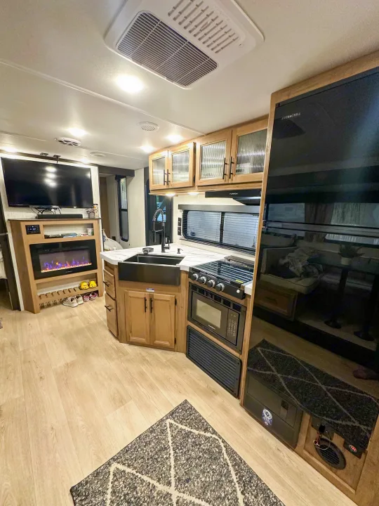 Bright RV rental interior, showcasing a modern kitchen, full-size refrigerator, living area, and entertainment center.. Forest River Grey Wolf 26 DBH 2025