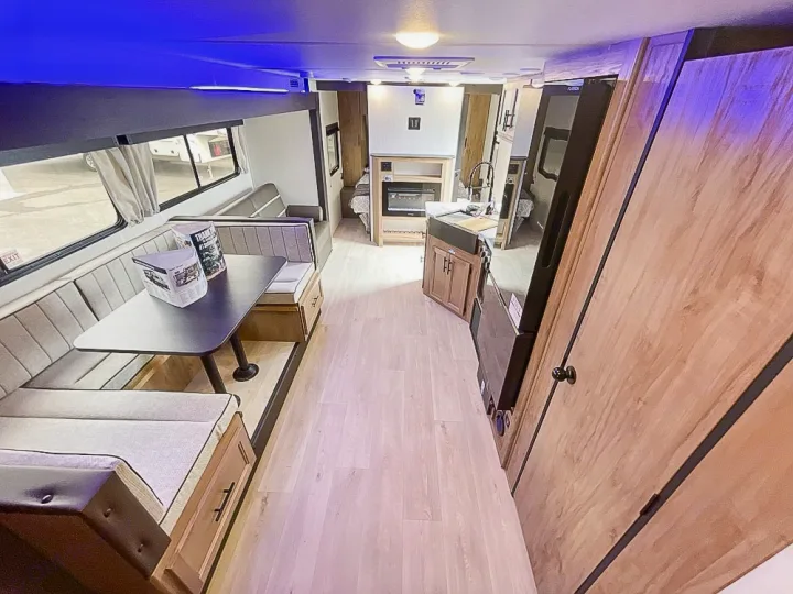 Inside a spacious rv rental: light-filled dinette, kitchen, and living area with a fireplace. Ideal for family trips.. Forest River Grey Wolf 26 DBH 2025