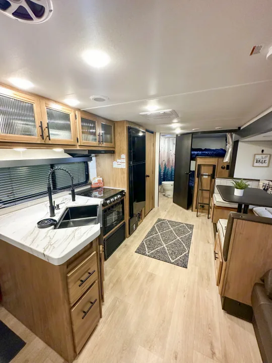 Spacious RV rental interior with kitchen, dining area, bathroom, and bunk beds. Perfect for family adventures!. Forest River Grey Wolf 26 DBH 2025