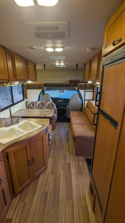 Spacious rv rental interior showing kitchen, dining booth, sofa, and front cockpit area.. Forest River Coachmen Freelander 2013