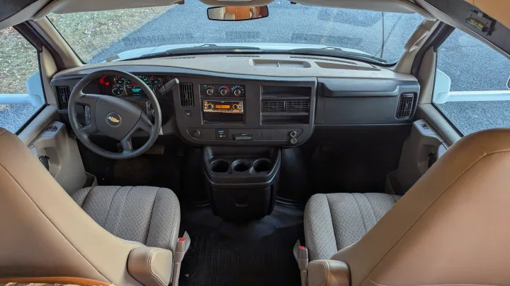 View inside an RV rental cockpit, detailing the Chevrolet dashboard, steering wheel, and front seats of the van.. Forest River Coachmen Freelander 2013