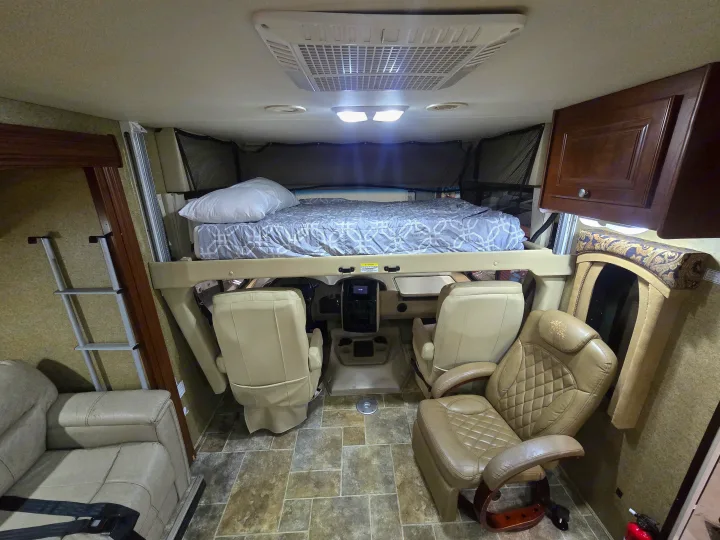 RV rental interior: elevated cab-over bunk, driver's cockpit, and lounge seating for comfortable travel.. Thor Motor Coach Miramar 2014