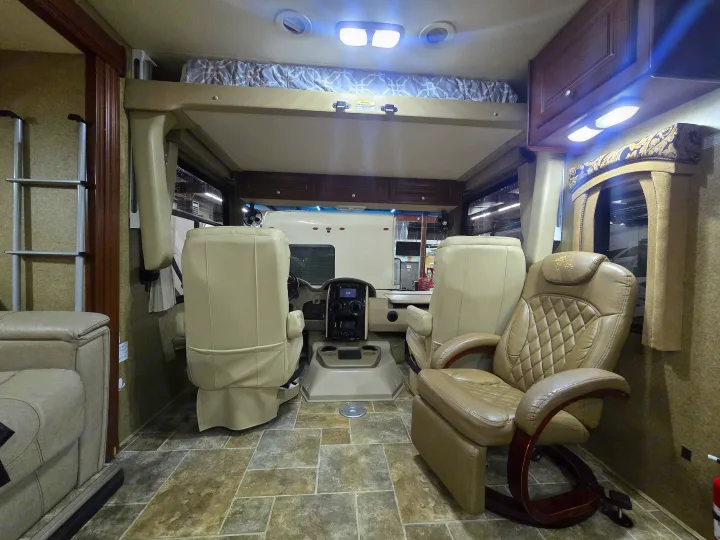 RV rental interior showcasing the front cabin, comfortable driver/passenger seats, overhead bed, and lounge chair. Tiled floor.. Thor Motor Coach Miramar 2014
