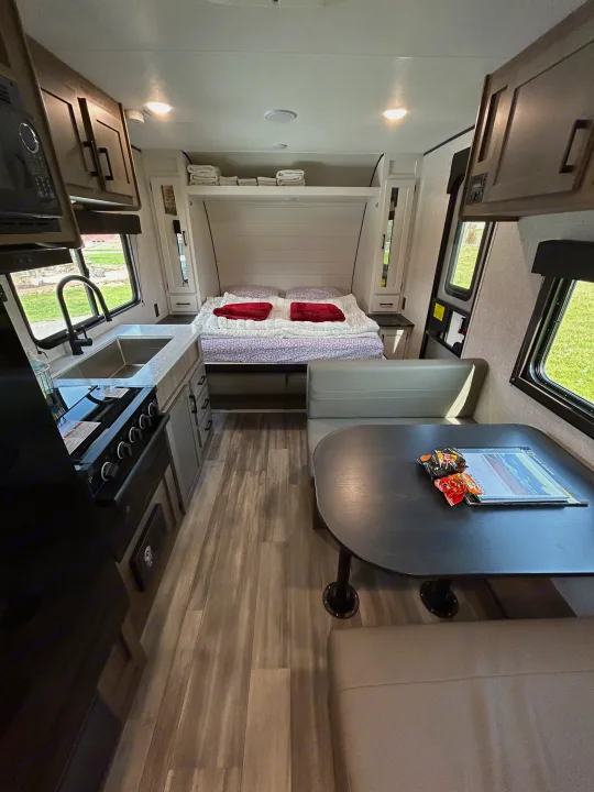 Explore this inviting RV rental interior: kitchen with a sink & stove, fold-down bed, and dinette. Perfect for travel.. Starcraft Autumn Ridge 2025