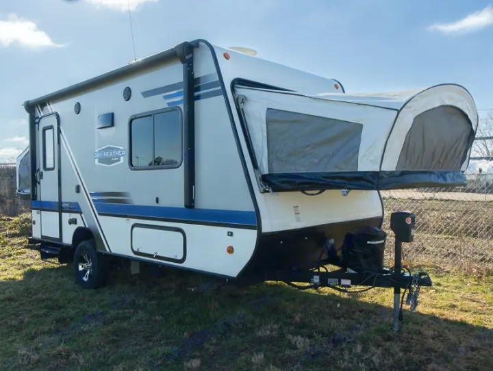 Modern grey and white hybrid travel trailer RV with pop-out beds, ideal for an rv rental. Parked on green grass.. Jayco Jay Feather 2018