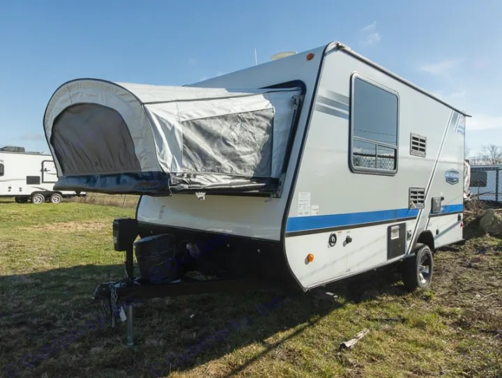 Compact grey & blue hybrid travel trailer, ideal for an RV rental. Features a front pop-out tent section on grass.. Jayco Jay Feather 2018