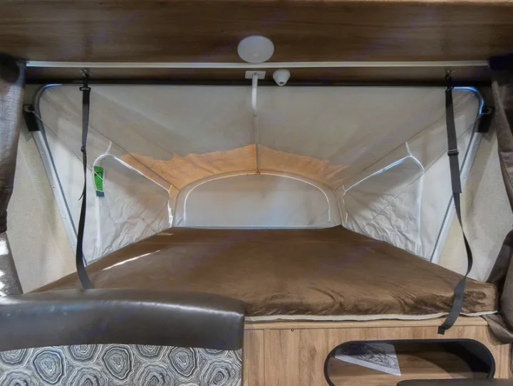RV rental interior: Pop-up camper bed with brown blanket and fabric walls, showing a cozy expandable sleeping area.. Jayco Jay Feather 2018
