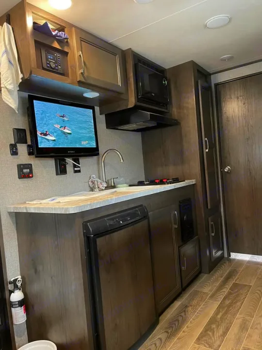 Compact RV rental interior with a functional kitchen, TV, fridge, and ample storage, perfect for travel.. Jayco Jay Flight SLX 2021