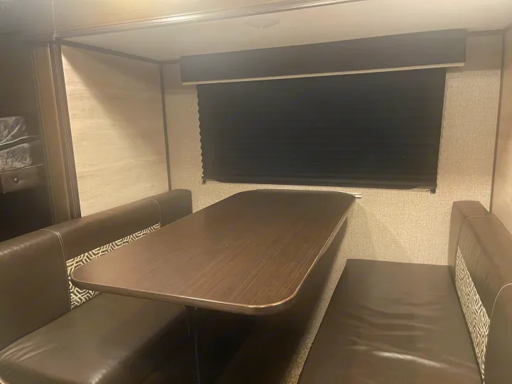 RV rental interior: A modern dinette with a dark wood table and brown leatherette booth seats, featuring patterned accents.. Jayco Jay Flight SLX 2021