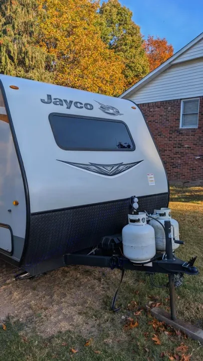 Front view of a Jayco travel trailer. This RV rental is parked with two propane tanks, ready for autumn trips.. Jayco Jay Flight SLX 2021