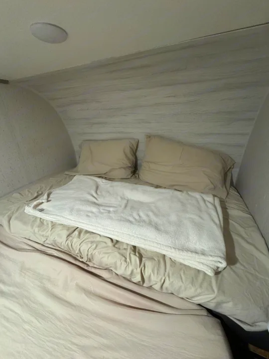 Cozy sleeping space in an RV rental featuring a comfortable bed with light bedding and curved interior walls.. Dutchmen Other 2023