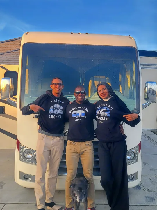 Smiling family and their dog pose by their large RV rental motorhome.. Thor Axis 2021