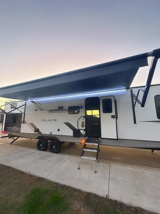 Experience outdoor adventures with this RV rental! Brightly lit with an extended awning and open door at dusk.. Crossroads RV Volante 2023