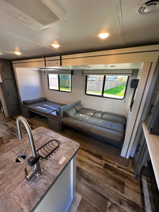 Inside an RV rental: modern kitchen, versatile living space with sofa bed and dinette, perfect for road trips.. Crossroads RV Volante 2023