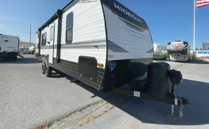 New white and black 'Hideout' travel trailer RV, ready for rv rental. Features an awning & front storage. Parked outside.. Keystone RV Hideout 2023