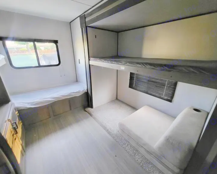 RV rental bunkhouse: Features a windowed bed, two bunk beds, and a gray sofa on a rug.. Keystone Hideout 2021