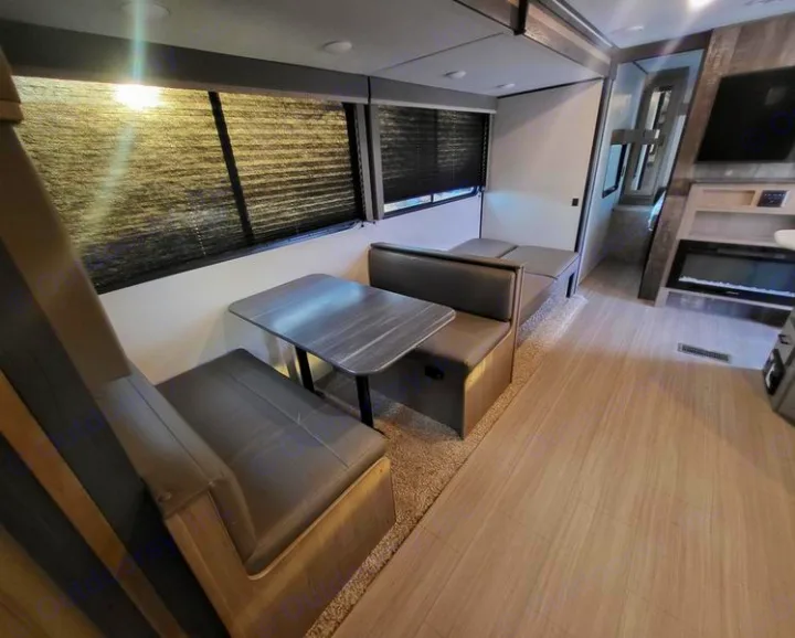 Spacious RV rental interior featuring a dinette, bench seating, and an entertainment center with a fireplace.. Keystone Hideout 2021