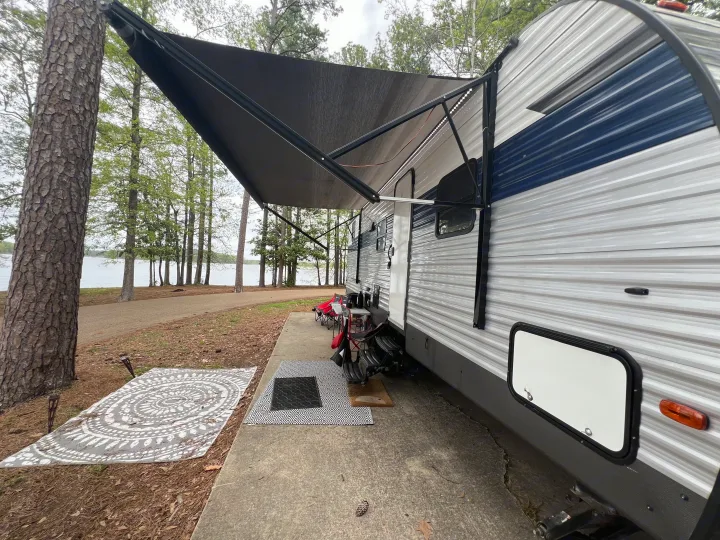 Lakeside RV rental with an extended awning, outdoor rugs, and seating provides a peaceful retreat. Perfect for camping.. Avenger LE 2022