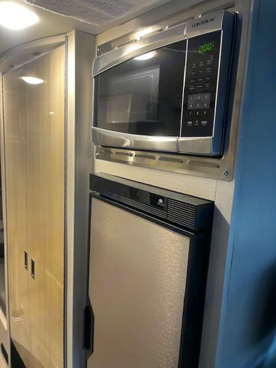 RV rental's kitchen area with a sleek stainless microwave and compact refrigerator for on-the-go meals.. Thor Tranquility 2023