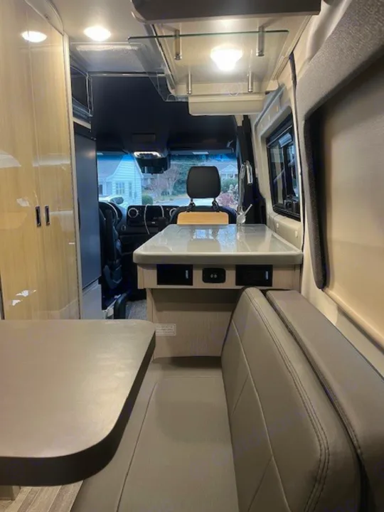 Spacious RV rental interior with modern kitchen, dining booth, and front view of a house.. Thor Tranquility 2023