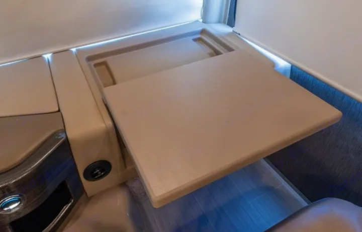 A light-colored pull-out table extends from an RV rental interior, with a USB port & ambient lighting.. Thor Challenger 2021