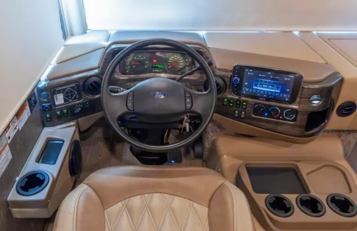 Inside an RV rental: driver's view of the dashboard, steering wheel, infotainment, and controls.. Thor Challenger 2021
